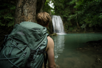Backpacker met groene NOMAD backpack bij een waterval