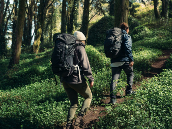 Man en vrouw wandelen in het bos met NOMAD backpacks op hun rug