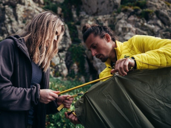 Groene NOMAD tent wordt in elkaar gezet door twee kampeerders