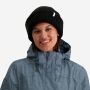 NOMAD Turoa Beanie dames zwart gebreide muts met logo gedragen door vrouw met blauwe outdoorjas