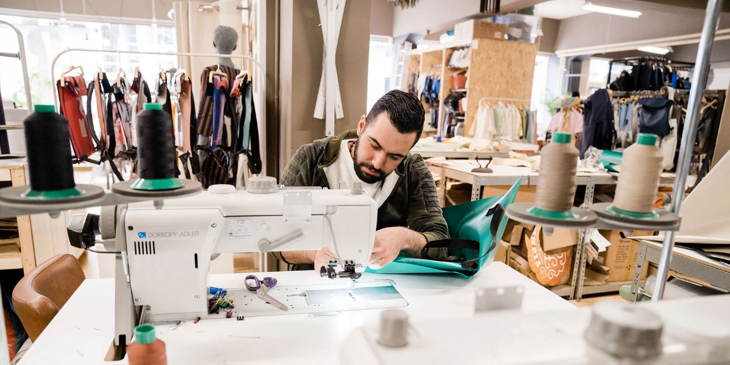 Man achter een naaimachine in een kledingatelier