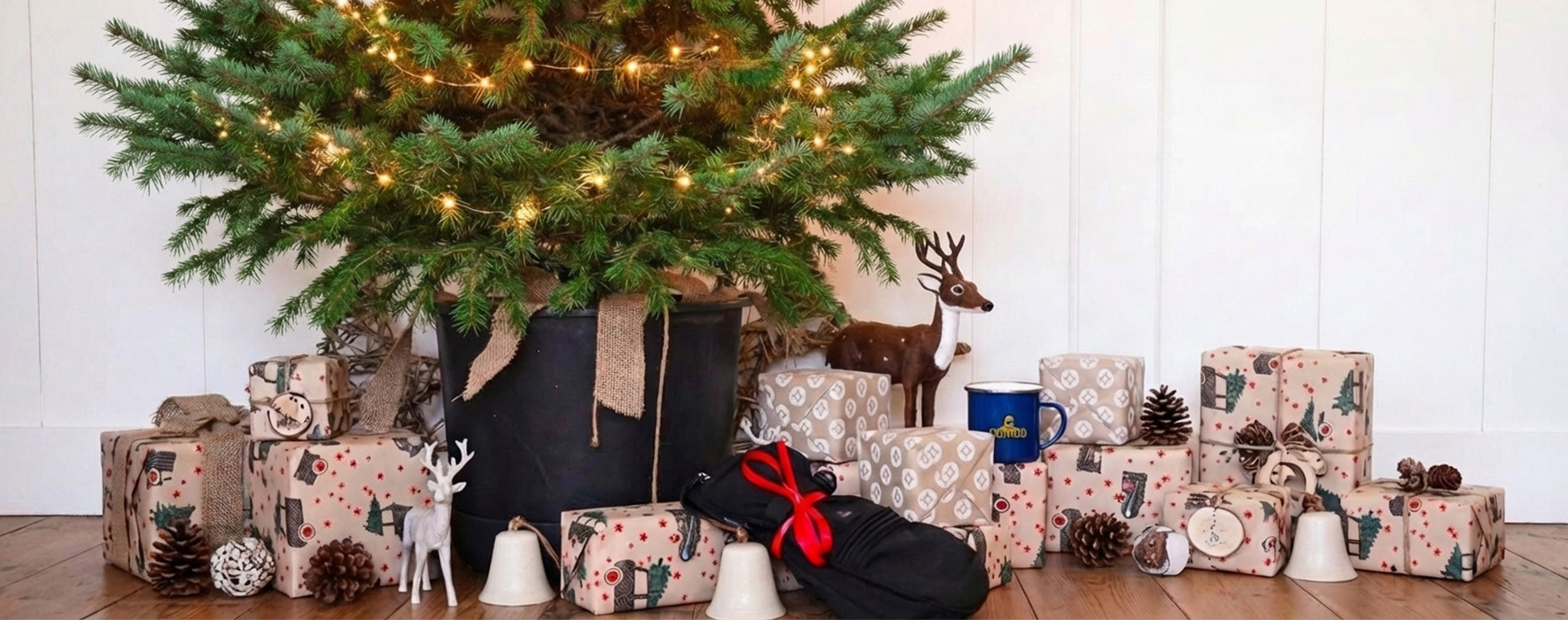 Sherpa handschoenen ingepakt in een doos met kerstversiering en een kerstboom op de achtergrond.
