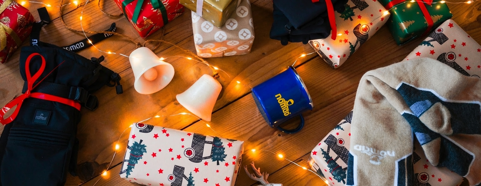 Sherpa handschoenen ingepakt in een doos met kerstversiering en een kerstboom op de achtergrond.