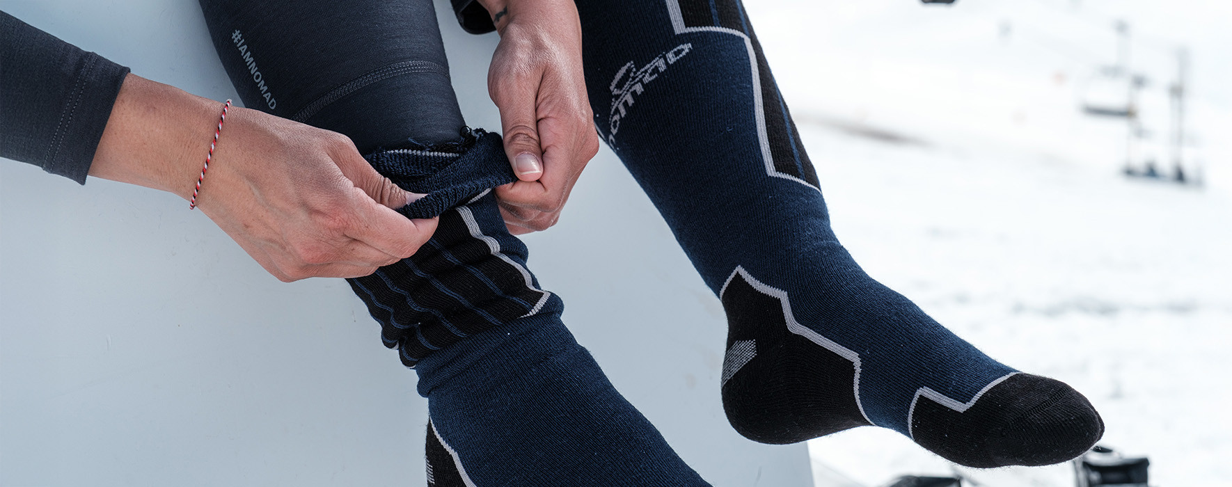 Vrouwenhanden die een skisok aantrekt in een besneeuwde omgeving. 