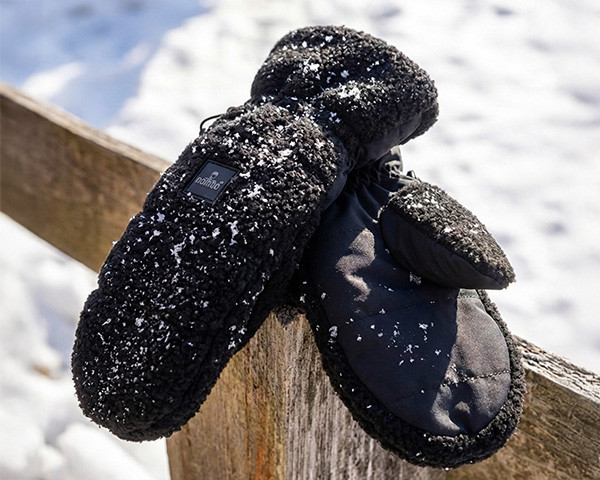 Handschoenen van een teddystof op een houten hek