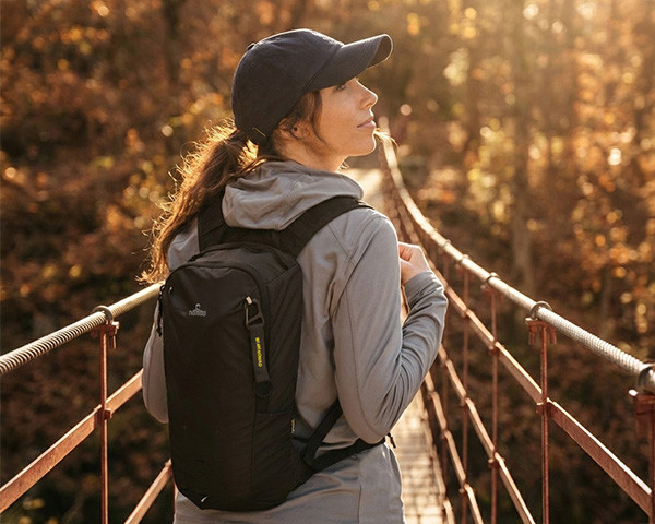 Frau mit Rucksack auf einer Fußbrücke